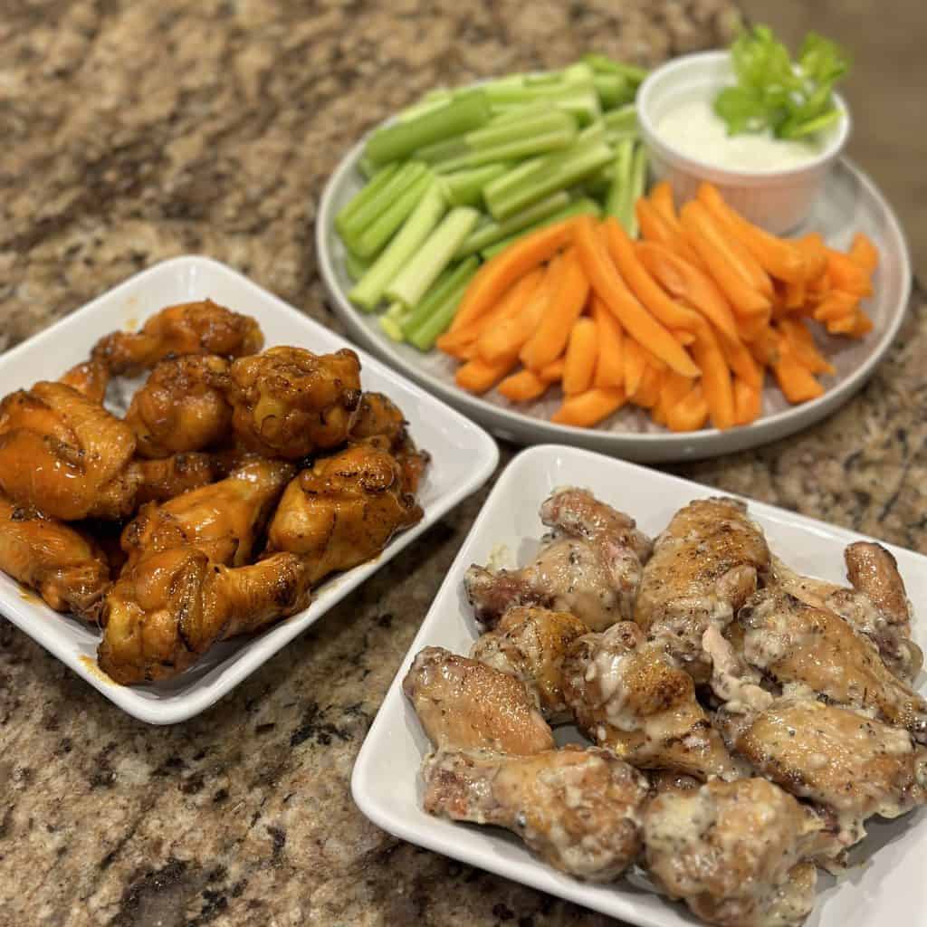 plates of sauced wings with carrots and celery on the side