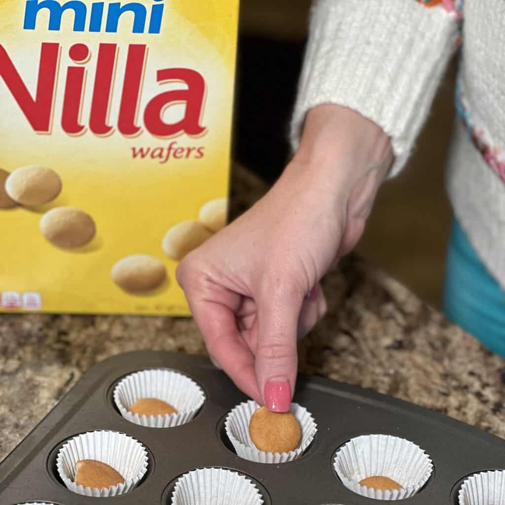 placing Nilla wafers into a muffin pan lined with cupcake liners