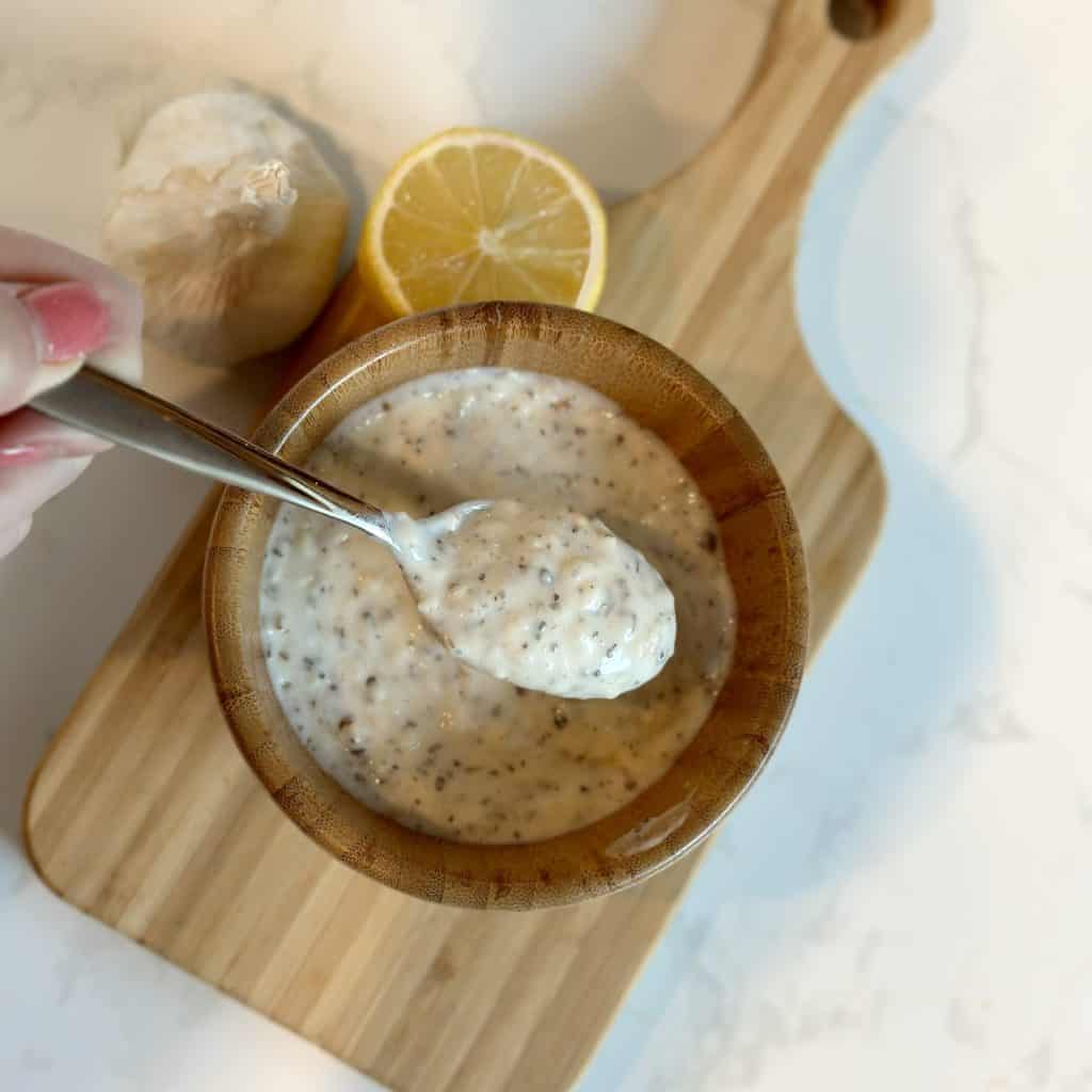 a spoonful of garlic parmesan sauce above a small serving bowl