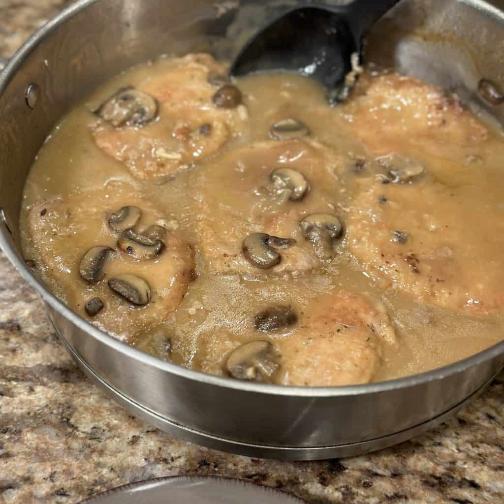 porkchops in a pan full of brown mushroom gravy