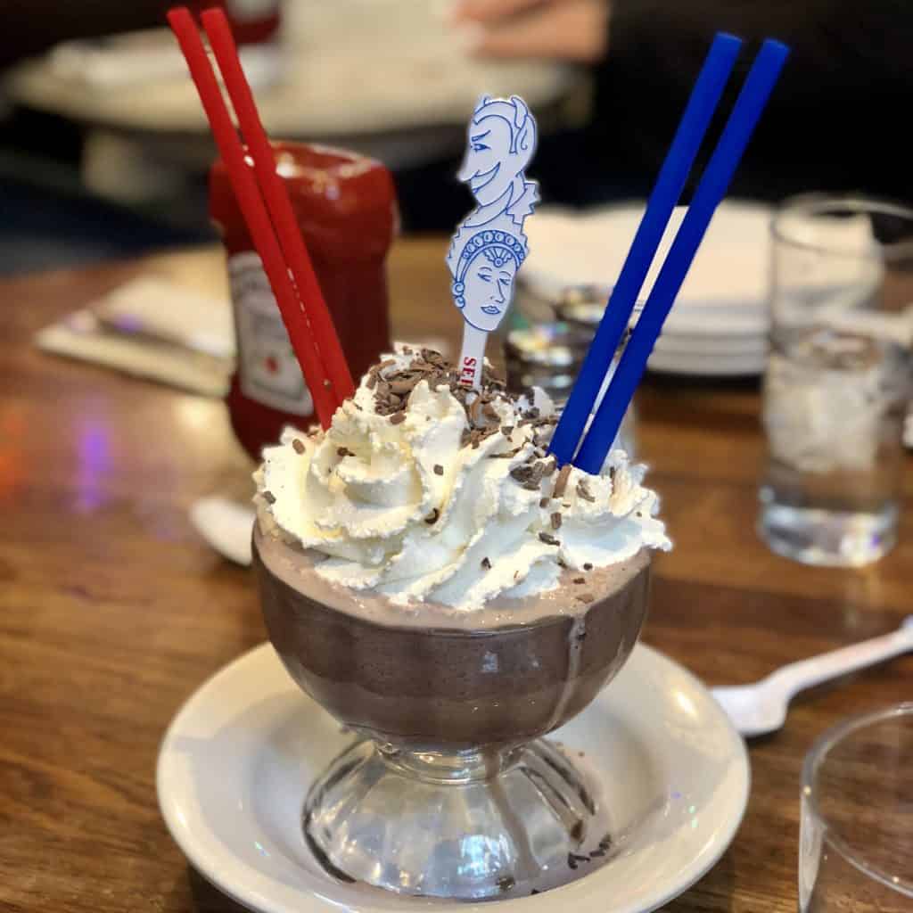 frozen hot chocolate with two sets of straws, one pair of red and one pair of blue in a decorative cup