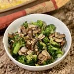This is a picture of a bowl of cooked broccoli and mushrooms.