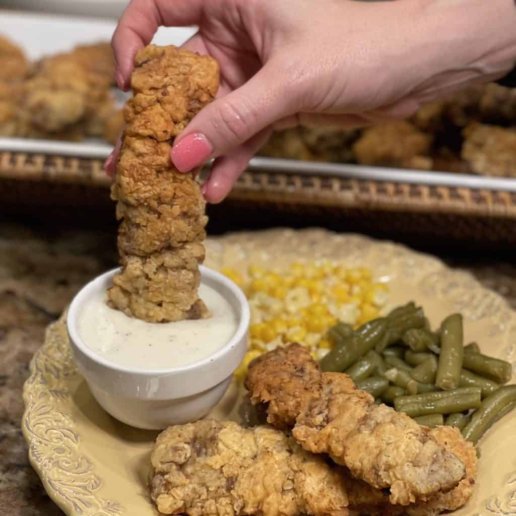 cube steak finger being dipped in country gravy