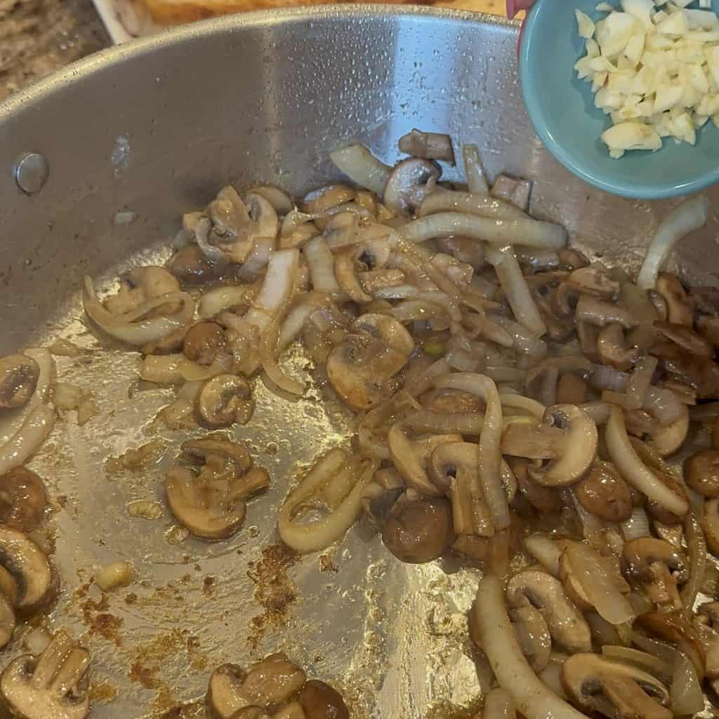 onions and mushrooms being cooked with garlic in a pan