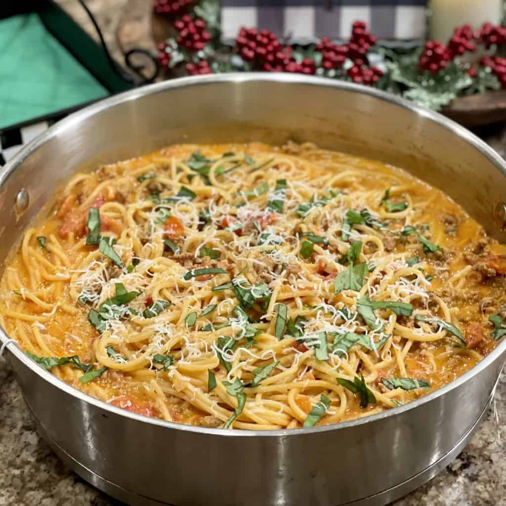 This is a picture of a pan of bolognese pasta with basil on top.