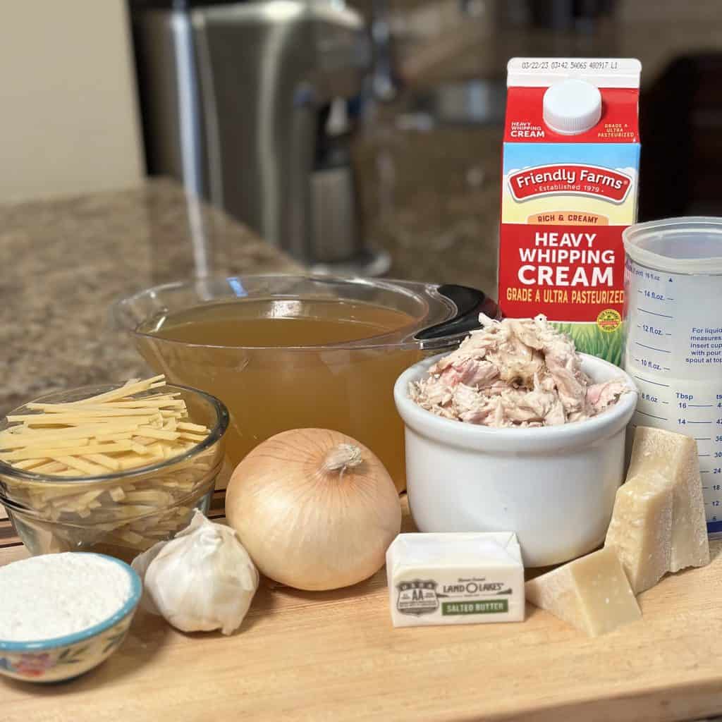 Ingredients for cheesy chicken alfredo soup arrayed on a cutting board