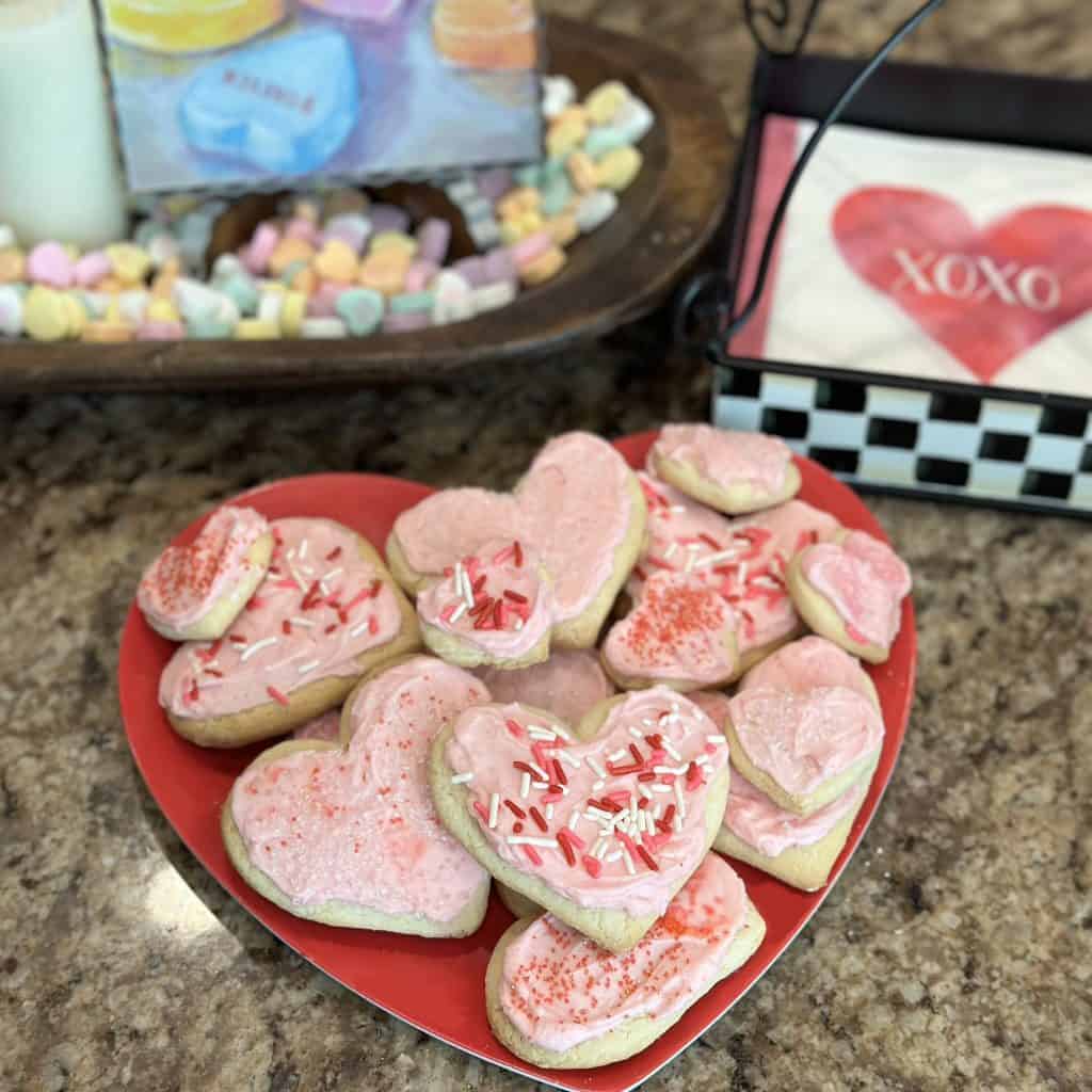 Heart-shaped cut out cookies with pink frosting on a heart-shaped plate