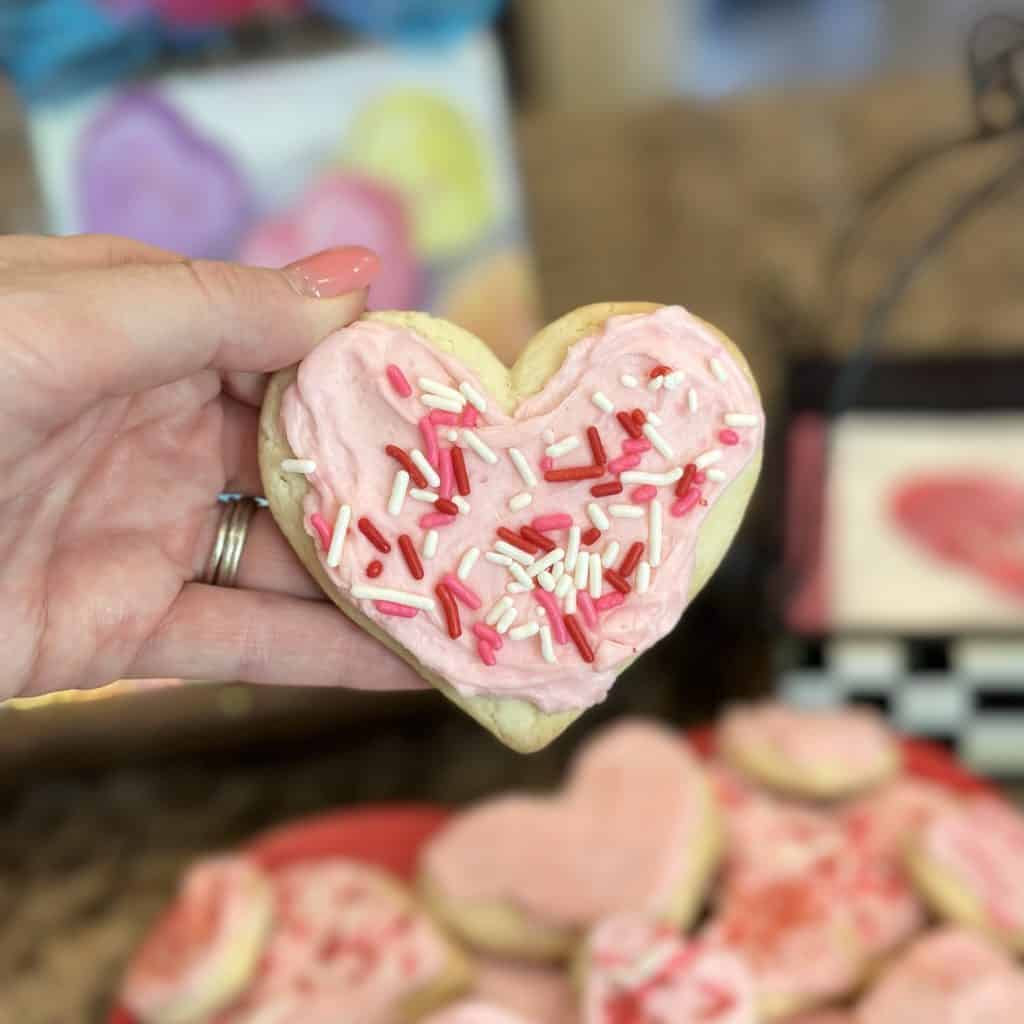 a heart-shaped cut out cookie with pink frosting and sprinkles