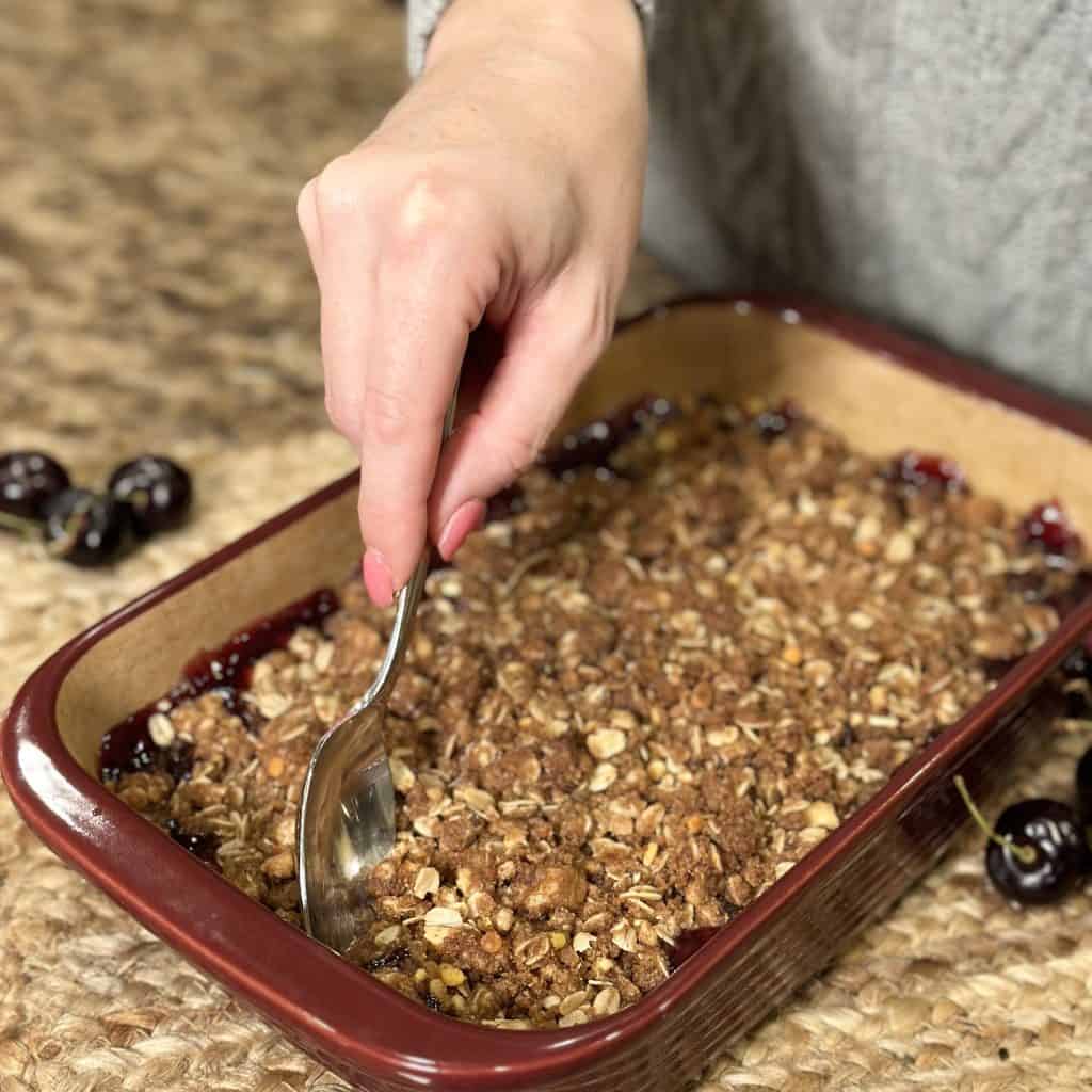 serving baked cherry crisp with a spoon