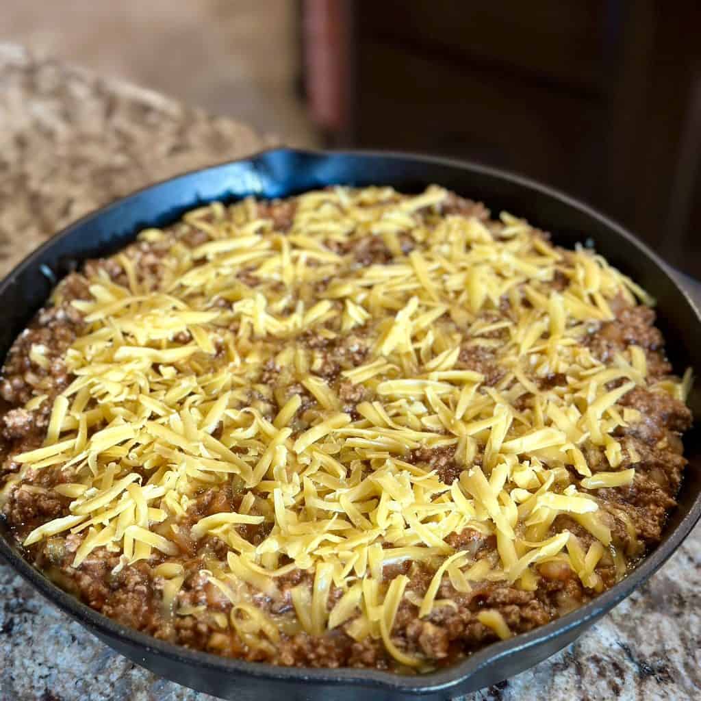 shredded cheddar topping a meat mixture in a pot