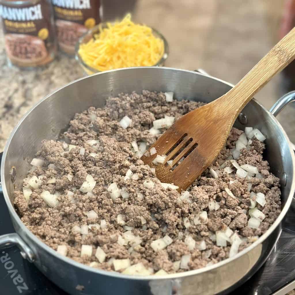 mixing ground beef and onions in a pot