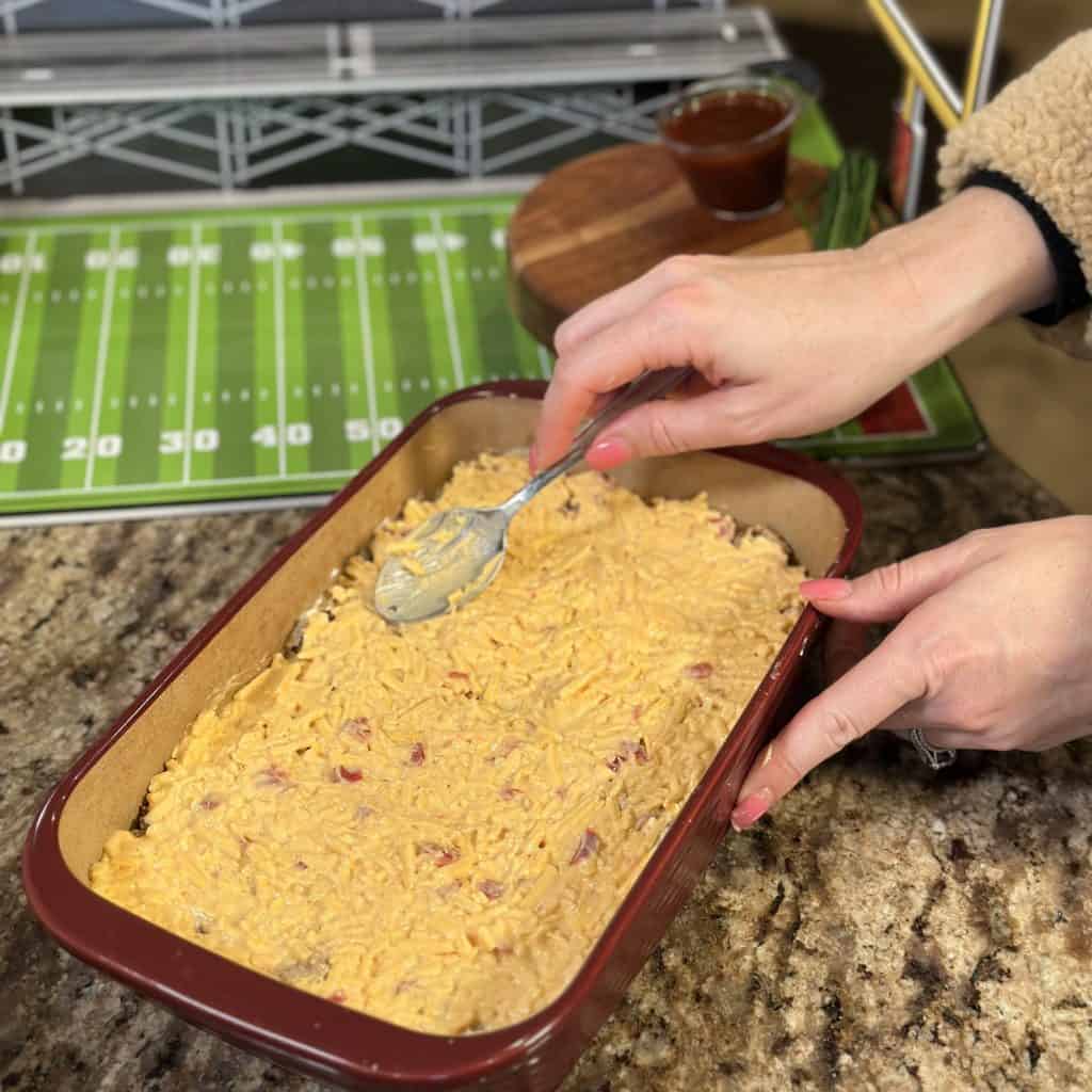 topping the cream cheese mixture with pulled pork and pimento cheese