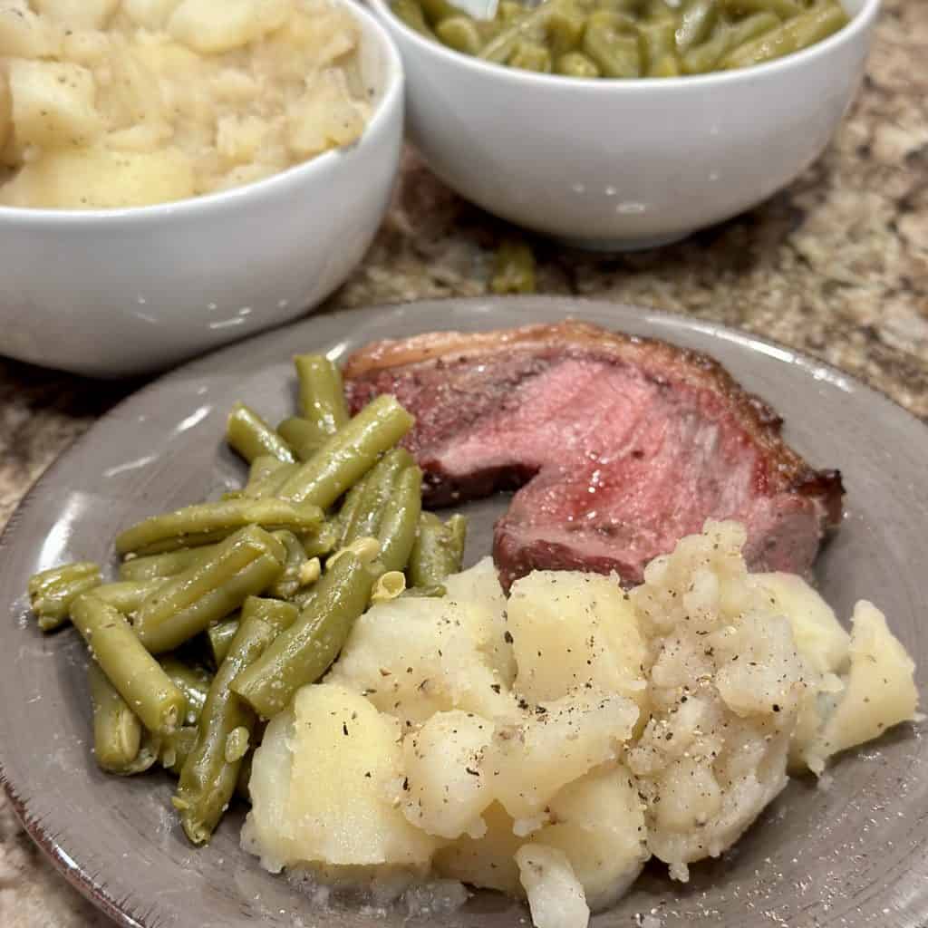 buttered potatoes plated with meat and green beans
