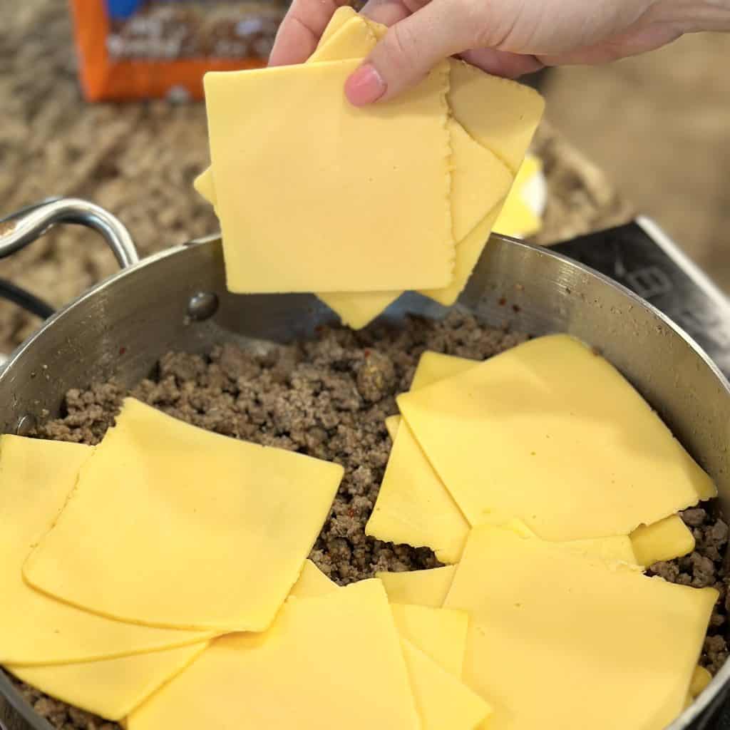 adding cheese slices to browned beef
