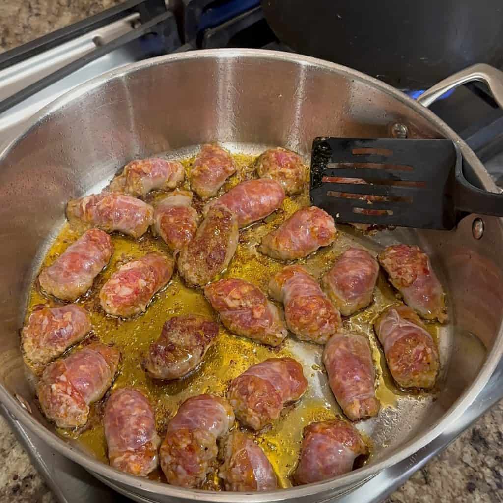 cooking sausage in oil in a high walled pan