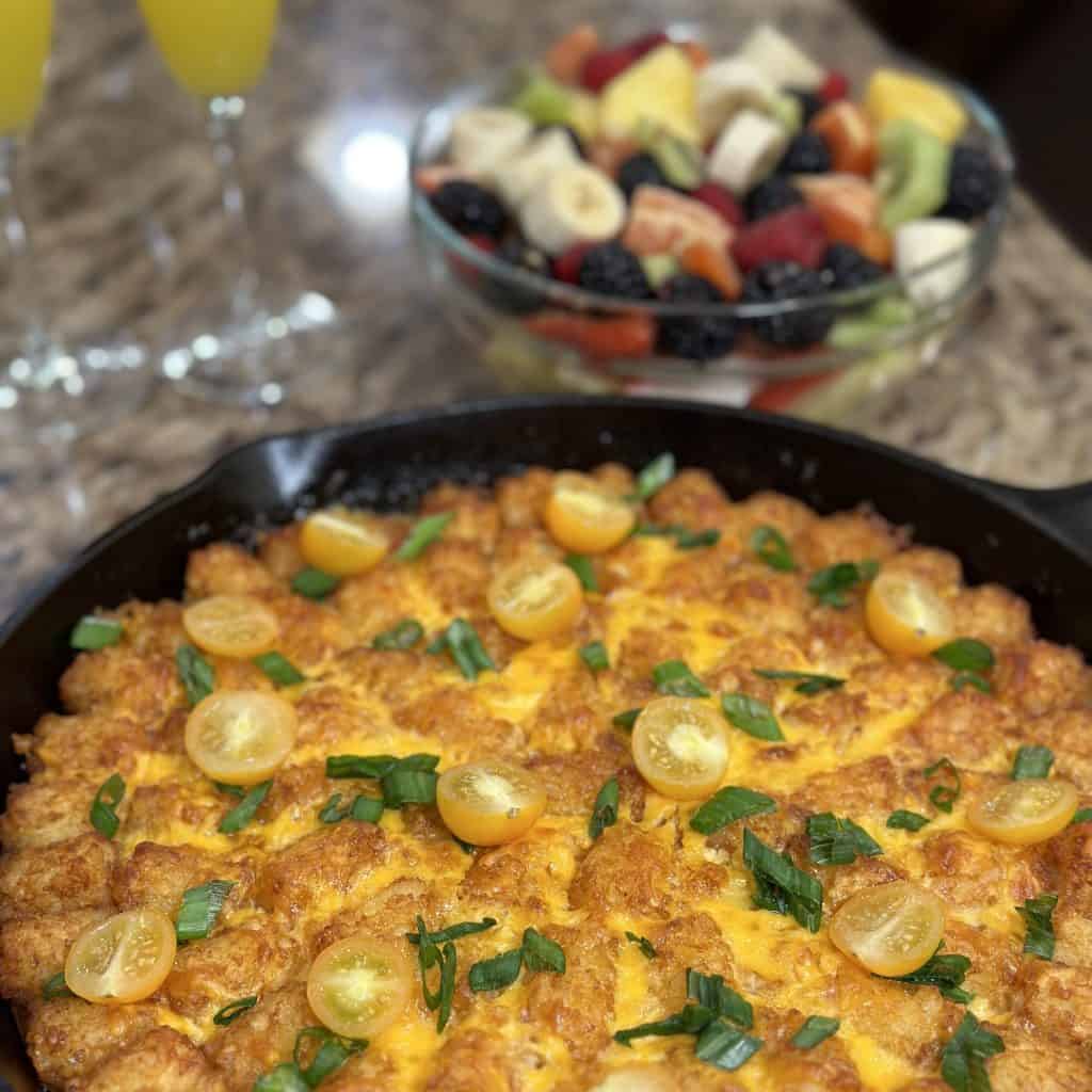 baked sunrise tater tot casserole, garnished with tomato halves and green onions