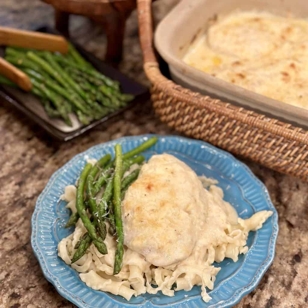 Plated chicken breast fillet with white cheese sauce and asparagus spears