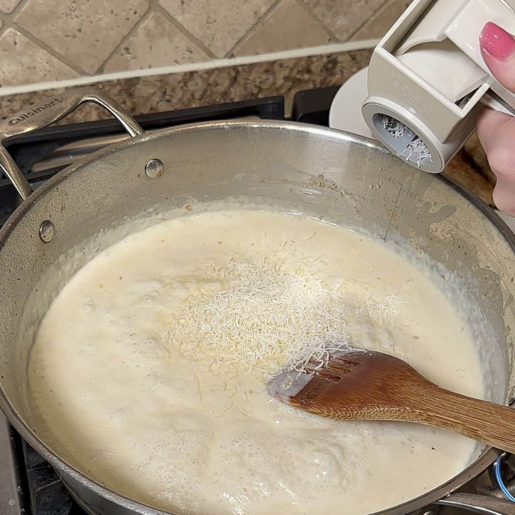 grating parmesan cheese into the sauce as it cooks