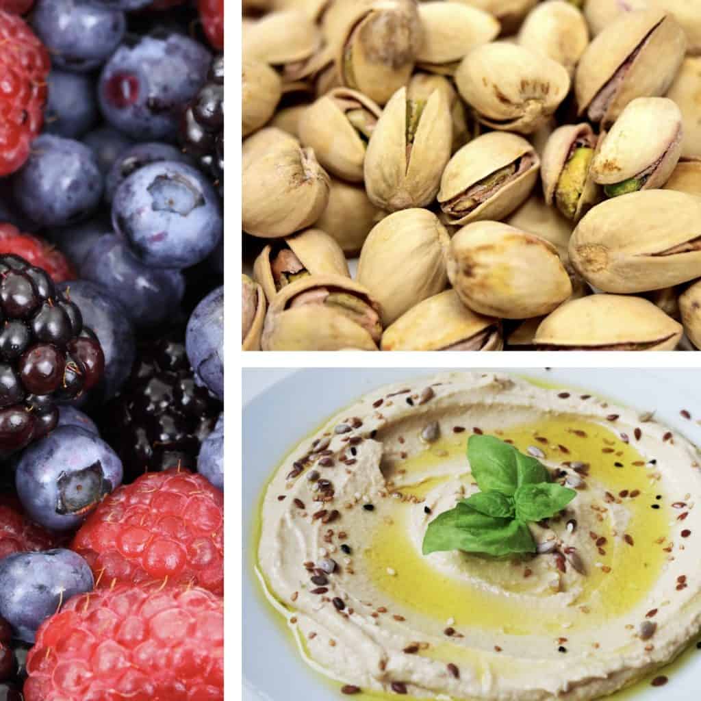 a closeup of various snacks, including mixed berries, pistachios, and hummus
