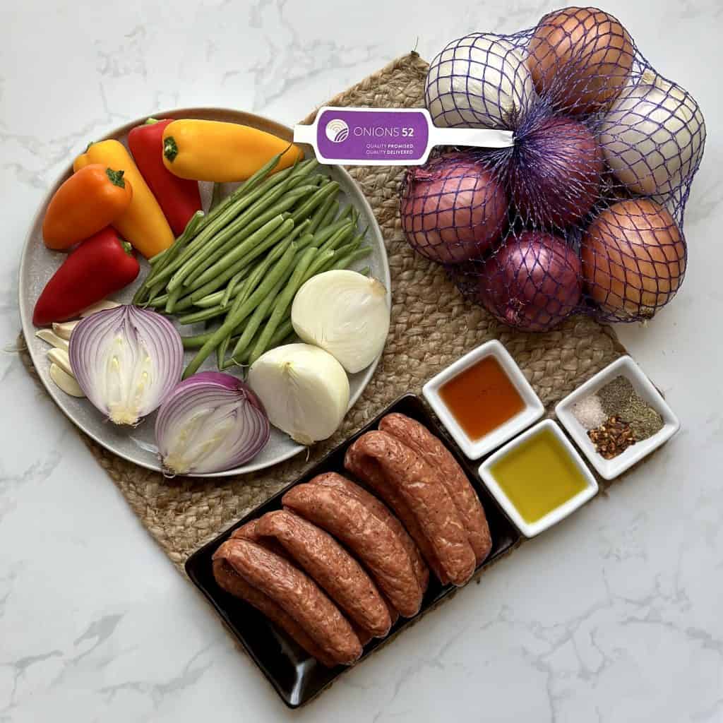 Ingredients for sausage and onions sheet pan meal nicely arranged on a decorative mat