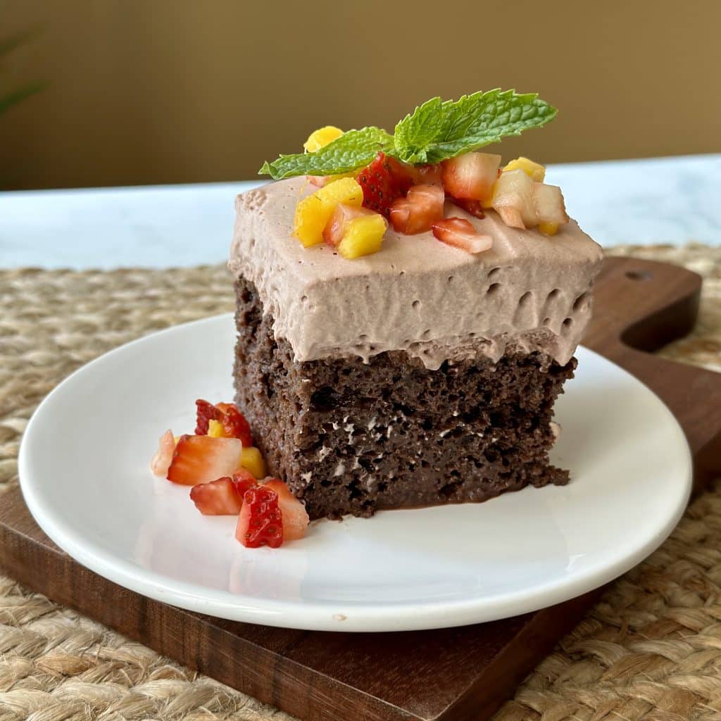 Chocolate Mocha Tres Leches cake garnished with mango, strawberries and mint