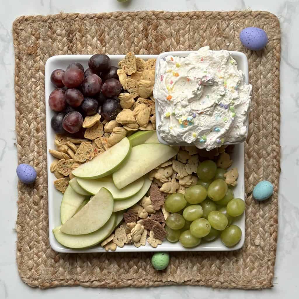 Finished cake batter sprinkle dip displayed with fresh fruit on a decorative mat