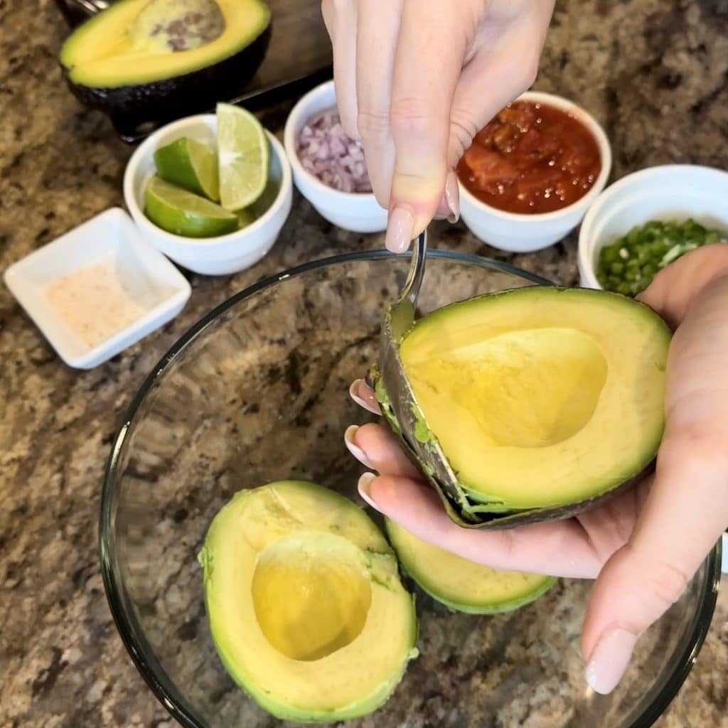 An avocado getting the flesh scooped away from the skin.