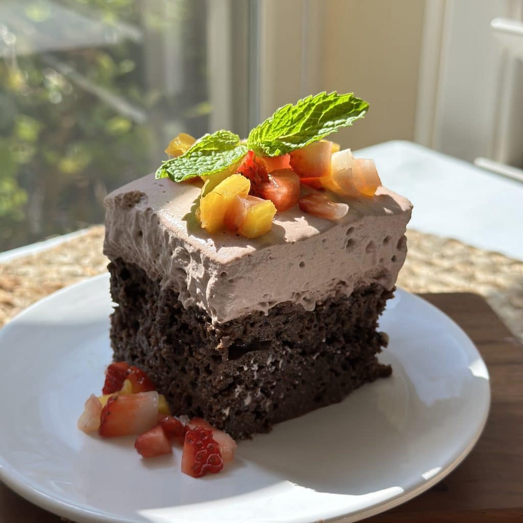 Chocolate Mocha Tres Leches cake garnished with mango, strawberries and mint