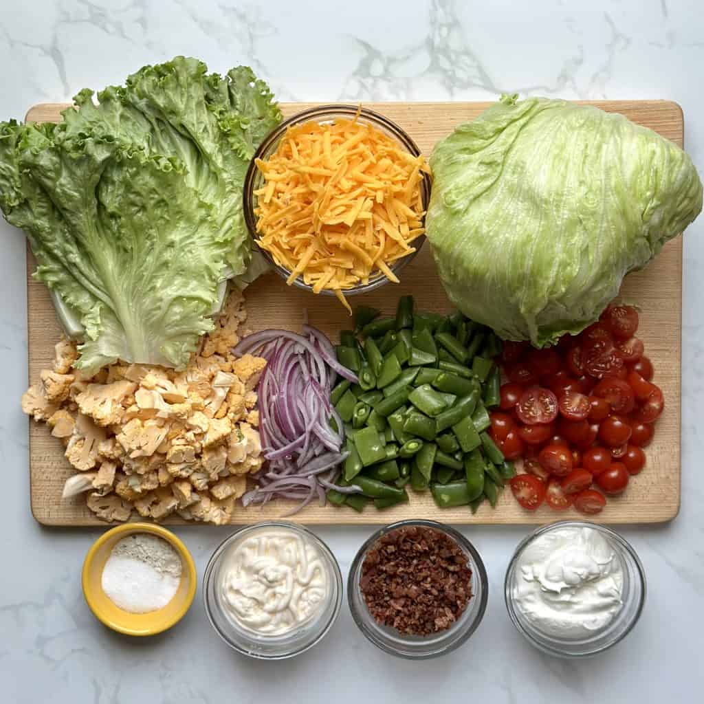 Ingredients for layered salad displayed nicely on a cutting board