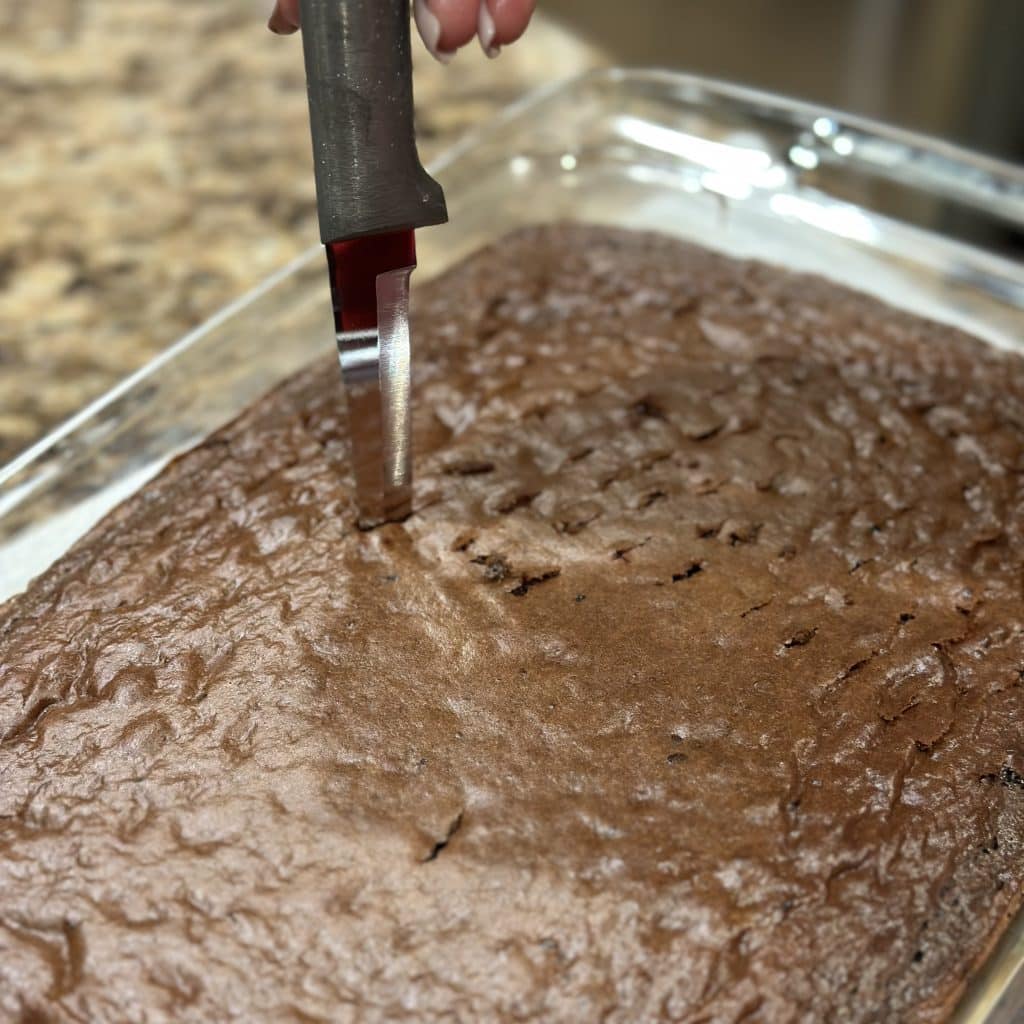 Using a knife to poke holes in the cake