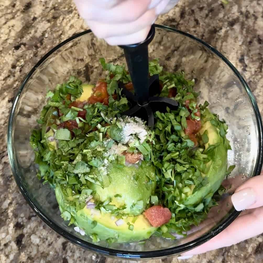 The ingredients to make guacamole being mixed in a bowl