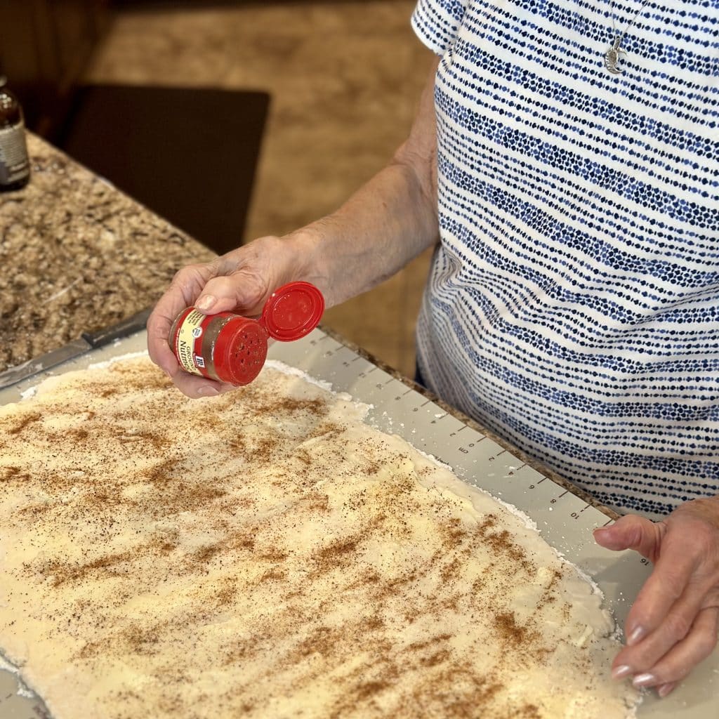 sprinkling nutmeg on the dough