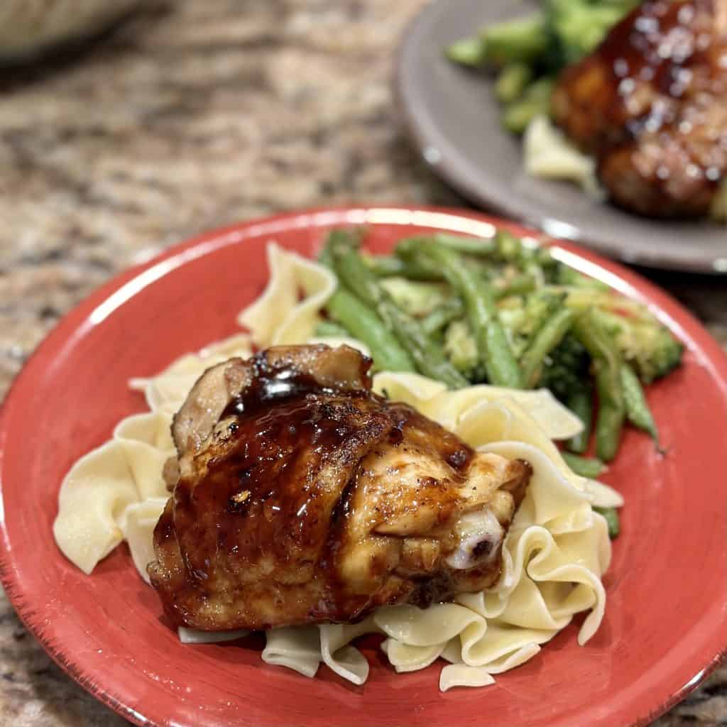 plated chicken on a bed of noodles and vegetables