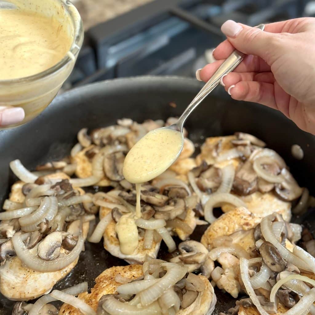 sautéed mushrooms and onions on par-cooked chicken being drizzled with  honey-Dijon mayo