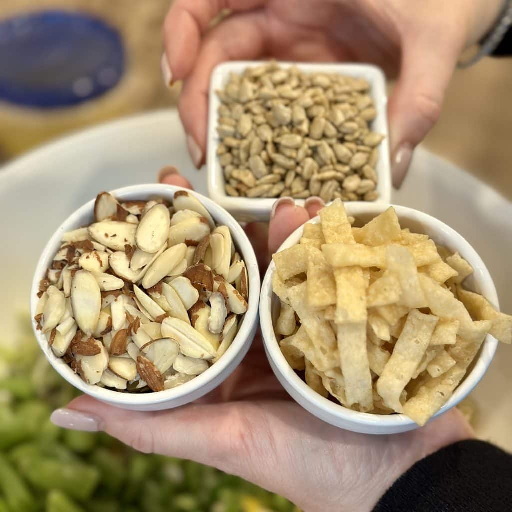 three small bowls containing nuts and crunchy strips of wonton