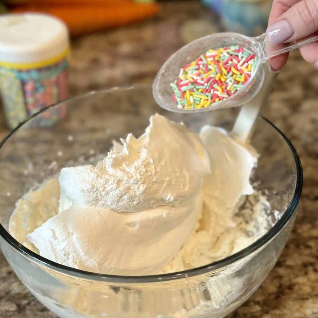Adding the sprinkles to the mixed cake batter dip