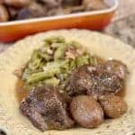 A dinner plate topped with green beans, roast beef and potatoes.