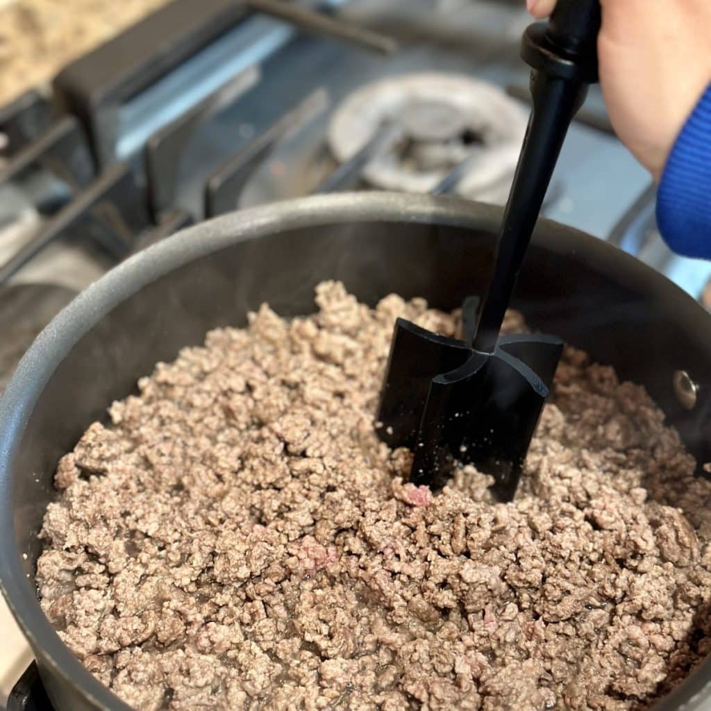 Ground beef being crumbled and cooked in a skillet