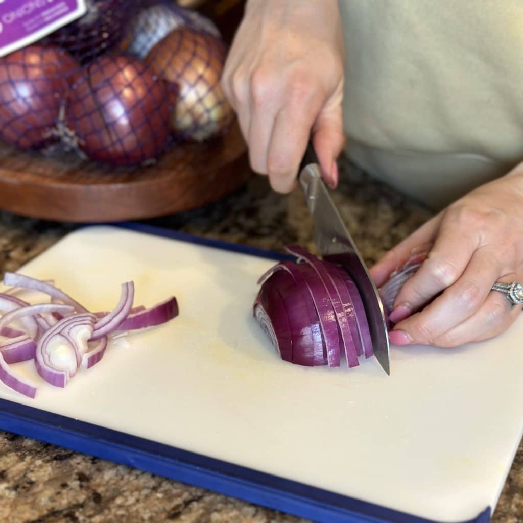 Slicing a red onion on a cutting board.