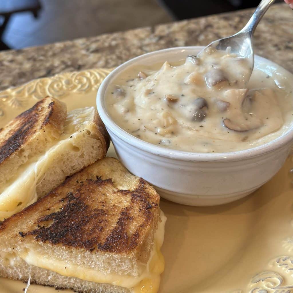 A bowl of cream of mushroom soup with a grilled cheese sandwich