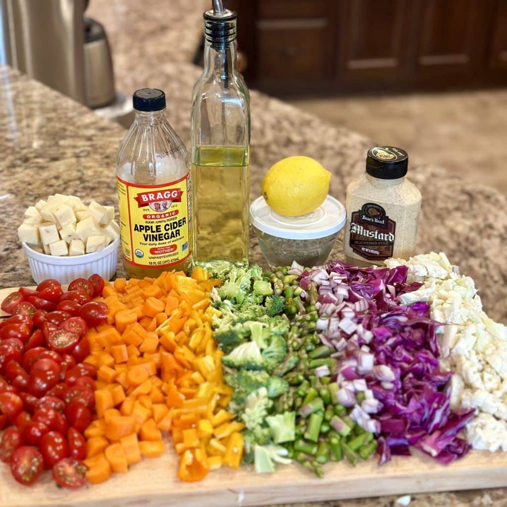 The ingredients to make a marinated vegetable salad arranged nicely in a rainbow pattern