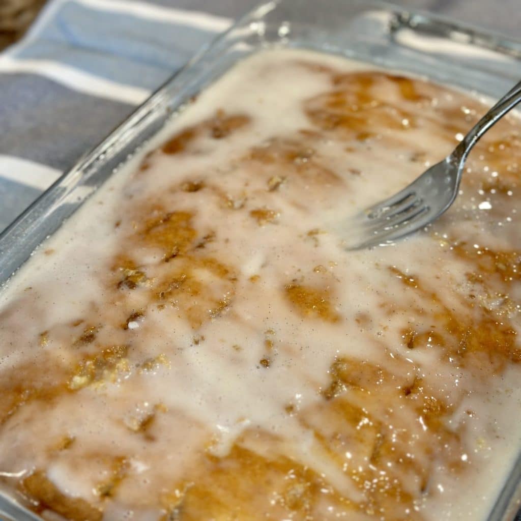 Spreading white glaze over the top of a hot cake.