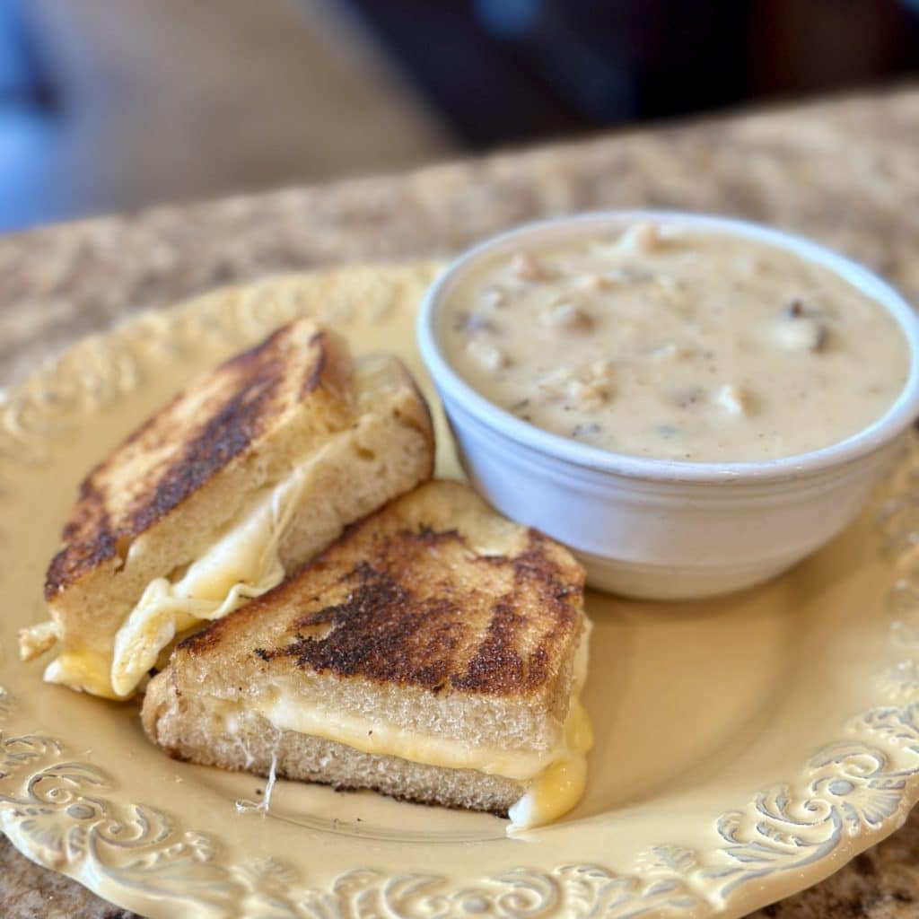 Grilled cheese sandwich and bowl of Homemade Cream of Mushroom Soup arranged on a plate