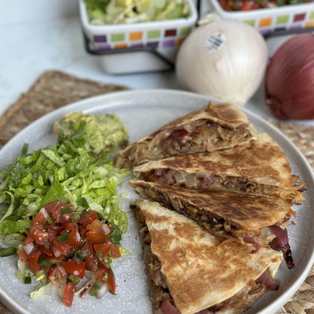 sliced quesadilla with shredded lettuce and pico de gallo