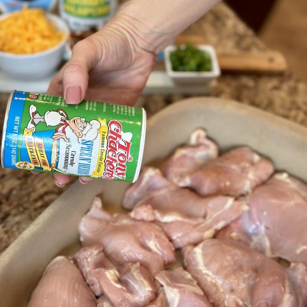 A pan of chicken being seasoned with seasoning salt