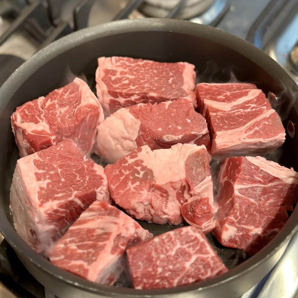 Beef searing in a large skillet
