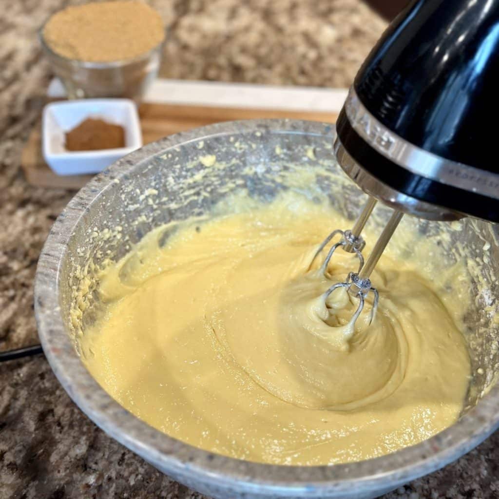 Yellow cake batter being mixed in a bowl with a hand mixer
