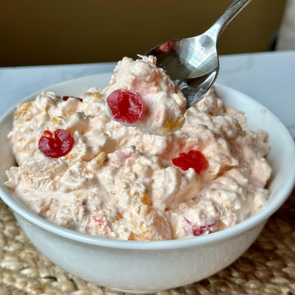 A picture of an orange jello salad. It’s light orange and white with accents of maraschino cherries