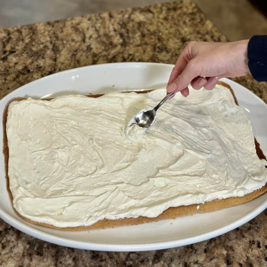 Cream cheese frosting being spread on a sugar cookie.