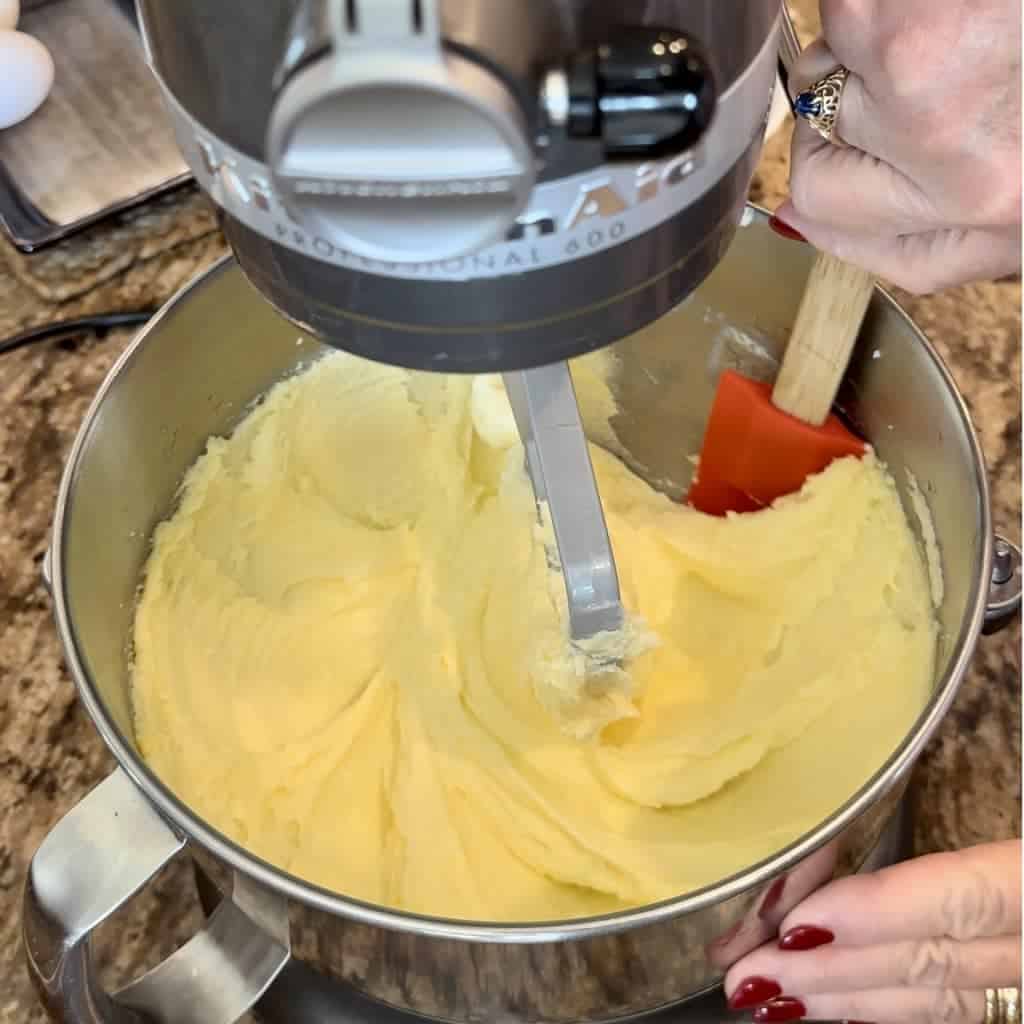 Scraping down batter from the sides of a mixing bowl with a spatula.